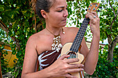 Schöne einheimische Frau spielt Ukulele neben dem Hafen von Bora Bora Vaitape, Gesellschaftsinseln, Französisch-Polynesien, Südpazifik.
