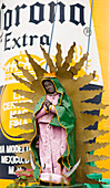 Religiöse Skulptur vor einer aufblasbaren Bierflasche in der Corona-Brauerei in Guadalajara, Mexiko.
