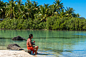 Insel Taha'a, Französisch-Polynesien. Ein einheimischer Junge spielt Ukulele, um ein Mädchen auf dem Motu Mahana zu umwerben, Taha'a, Gesellschaftsinseln, Französisch-Polynesien, Südpazifik.