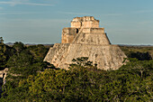 Die Westfassade der Pyramide des Magiers, auch bekannt als Pyramide des Zwerges. Sie ist das höchste Bauwerk in den prähispanischen Maya-Ruinen von Uxmal, Mexiko, und ragt etwa 35 Meter in die Höhe. Der Tempel am oberen Ende der Treppe ist im Chenes-Stil gebaut, während der obere Tempel im Puuc-Stil gehalten ist.