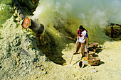 Sulphur Miner Working at Kawah Ijen, Java, Indonesia. Kawah Ijen is a volcano with an active crater and acid lake in East Java, Indonesia. It is an unbelievable and unmissable destination for anyone visiting Java or Bali. Not only is the view on the 4km walk up to the craters edge impressive, but what goes on there is mind boggling. Walking down to the bottom of Kwah Ijen (Ijen Crater), hundreds of Indonesian men, many in flipflops, are mining sulphur from the heart of the volcano. They load their baskets up with up to 80kg of sulphur, before starting the arduous and extremely dangerous scramb