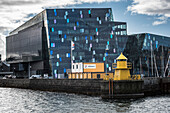 Konzertsaal und Konferenzzentrum Harpa mit gelbem Leuchtturm im Hafen von Reykjavik, Island