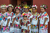 Frauen in traditionellen, festlich bestickten Huipils und geblümten Hüten bereiten sich auf den Tanz des Schweinekopfes und des Truthahns (Baile de la cabeza del cochino y del pavo) in Santa Eleana, Yucatan, Mexiko, vor. Dieser Festtanz der Maya wird nur einmal im Jahr aufgeführt.