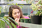 Young adult female gets up close to observe Venus flytrap (Dionaea muscipula) in greenhouse, College Park, Maryland