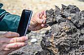 A man uses his phone to photograph a soil sample, Debre Berhan, Ethiopia