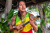 Einheimischer tätowierter Mann spielt Ukulele in Huahine, Gesellschaftsinseln, Französisch-Polynesien, Südpazifik.