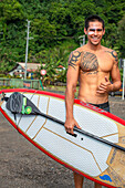 Surfer am Strand mit schwarzem Sand auf Pointe Venus, Tahiti, Französisch-Polynesien, Tahiti Nui, Gesellschaftsinseln, Französisch-Polynesien, Südpazifik.