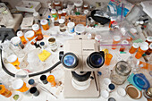 Lab facility with desktop of samples bottles, microscope, pill bottles, petri dishes