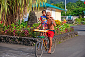 Tahitianischer Mann mit ihrer Tochter, die Baguettes auf dem Fahrrad auf der Insel Tahiti, Französisch-Polynesien, Tahiti Nui, Gesellschaftsinseln, Französisch-Polynesien, Südpazifik, tragen.