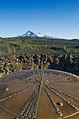 Bronzetafel, die auf Berggipfel hinweist, die man vom Dee Wright Observatory am McKenzie Pass in den Cascade Mountains in Oregon sieht, mit den vulkanischen Gipfeln North Sister und Middle Sister in der Ferne.