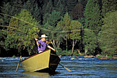 Angler fly fishing from a drift boat on the McKenzie River; Cascade Mountains, Lane County, Oregon.