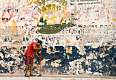 Mann fegt Bürgersteig und verblasste Schilder an der Wand, Avenida Zaragoza, Altstadt von Mazatlan, Mexiko.