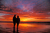 Zwei Freundinnen beobachten den unglaublichen Sonnenuntergang am Nye Beach, Newport, Küste von Oregon.
