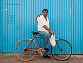 Mann auf einem Fahrrad vor einer blauen Wand, Tonal?, Mexiko.