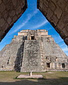 Die Westfassade der Pyramide des Magiers, die auch als Pyramide des Zwergs bekannt ist, zeigt in das Vogelviereck. Sie ist das höchste Bauwerk in den prähispanischen Maya-Ruinen von Uxmal, Mexiko, und ragt etwa 35 Meter in die Höhe. Der Tempel am oberen Ende der Treppe ist im Chenes-Stil erbaut, während der obere Tempel im Puuc-Stil gehalten ist.