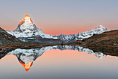 Wanderer bewundert das Matterhorn, das sich im Riffelsee bei Sonnenaufgang spiegelt, Gornergrat, Zermatt, Kanton Wallis, Schweiz, Europa