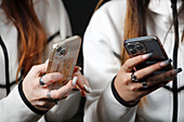 Female hands with smartphones close up, two women using mobile phones, France, Europe