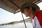 Junger männlicher Tourist auf einem überdachten Boot auf dem Rufiji-Fluss