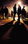 Clubber stehen am Ende der Nacht in Silhouette auf der Straße
