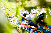 Frau im Gras liegend und lesend im Wald