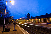 Frau auf dem Bahnsteig der Spean Bridge in der Abenddämmerung, als der Zug ankommt