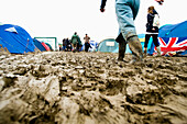 Wellies Passing Through Muddy Camp Site At Glastonbury