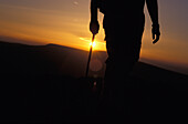 Silhouettierter Wanderer auf dem Black Mountain bei Sonnenuntergang, tiefer Blickwinkel