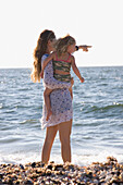 Mutter hält ihre kleine Tochter am Strand am Meer