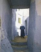 Einheimische Frau geht in der Gasse der Medina (ummauerte Stadt) spazieren