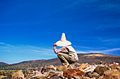 Person auf Felsen sitzend mit Blick auf die Landschaft
