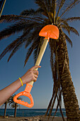 Person hält Spaten in der Nähe einer Palme am Strand