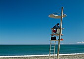 Rettungsschwimmer auf einem Turm am Strand sitzend