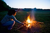 Woman Stoking Camp Fire