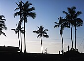 Silhouette von Menschen und Palmen in der Morgendämmerung neben der Kirche von Santo Antonio