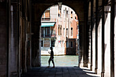 Woman Walking Through Arches Next To Over Grand Canal In Rialto District