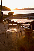 Tisch und Stühle im Freien am Wasser bei Sonnenuntergang, Lopud, Kroatien