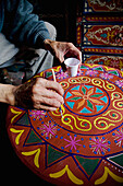 Mann bemalt Tisch im Souk, Nahaufnahme der Hand, Marrakesch, Marokko