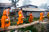 Novizenmönche sammeln am frühen Morgen Almosen im Wat Naluang, Luang Prabang, Nordlaos