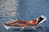 Young Woman Sunbathing On Sunlounger By Swimming Pool On Mayan Riviera, Yucatan Peninsular,Quintana Roo State,Mexico
