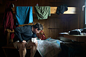Mann liest Karte in Wandererhütte, Kungsleden Trail, Abisko, Schweden