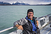 Ein Tourist sitzt auf einem Boot und posiert für ein Foto auf einer Kreuzfahrt auf dem Lago Argentino in der Nähe von El Calafate, argentinisches Patagonien; El Calafate, Provinz Santa Cruz, Argentinien