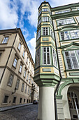Bunte Fassade der Ecke eines Wohngebäudes entlang einer Kopfsteinpflasterstraße; Prag, Tschechien