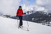 Eine weibliche Abfahrtsläuferin posiert für die Kamera auf einem Skihang in einem Skigebiet; Whistler, British Columbia, Kanada