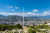 Ein Kreuz und Blick vom Gipfel eines Berges, der Mostar überblickt und die Trennung zwischen der Stadt zeigt; Mostar, Bosnien und Herzegowina