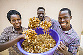 Staff holding a bucket full of an abundance of White ants (Isoptera); Gulu, Uganda