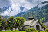 Mittelalterliche Kirche Les Praz de Chamonix und der Fuß der Aiguille Dru im Hintergrund; Chamonix-Mont-Blanc, Haute-Savoie, Frankreich.