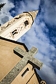Nahaufnahme von Steinkreuz und Kirche St. Panteleimon unter blauem Himmel; Courmayeur, Aostatal, Italien