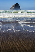 Muster am Strand mit einer großen Felsformation vor der Küste, Cape Kiwanda; Pacific City, Oregon, Vereinigte Staaten von Amerika