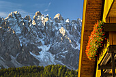 Nahaufnahme eines Holzchalets mit Blumenkästen und schroffem Gebirge im Hintergrund mit blauem Himmel; Grainau, Bayern, Deutschland