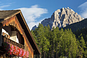 Wooden alpine chalet with flower boxes and mountain in the background with blue sky and clouds; Grainau, Bavaria, Germany